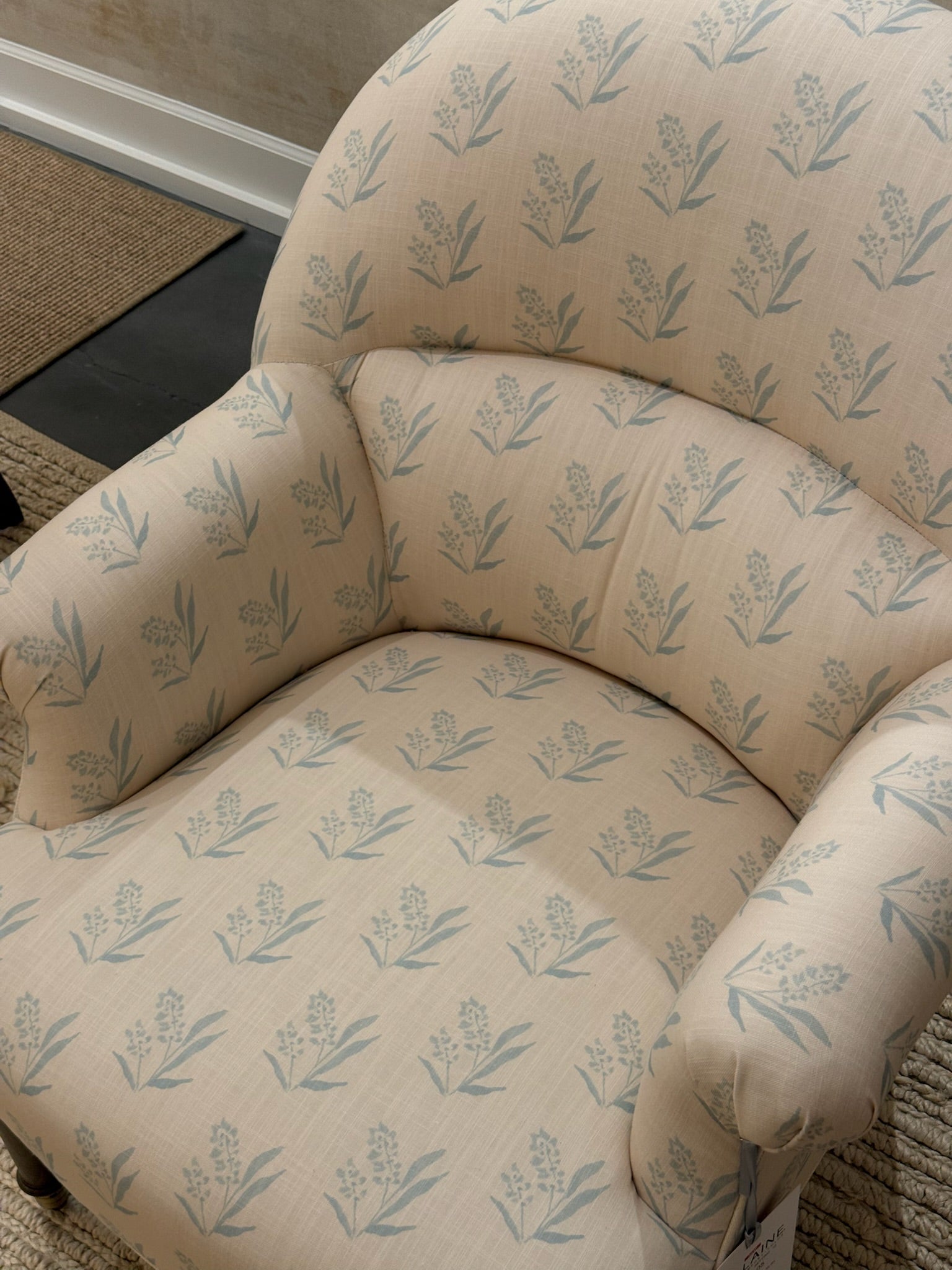EH x Renee Bouchon Marbella Sea linen fabric sample on an upholstered chair, featuring a light blue floral pattern.