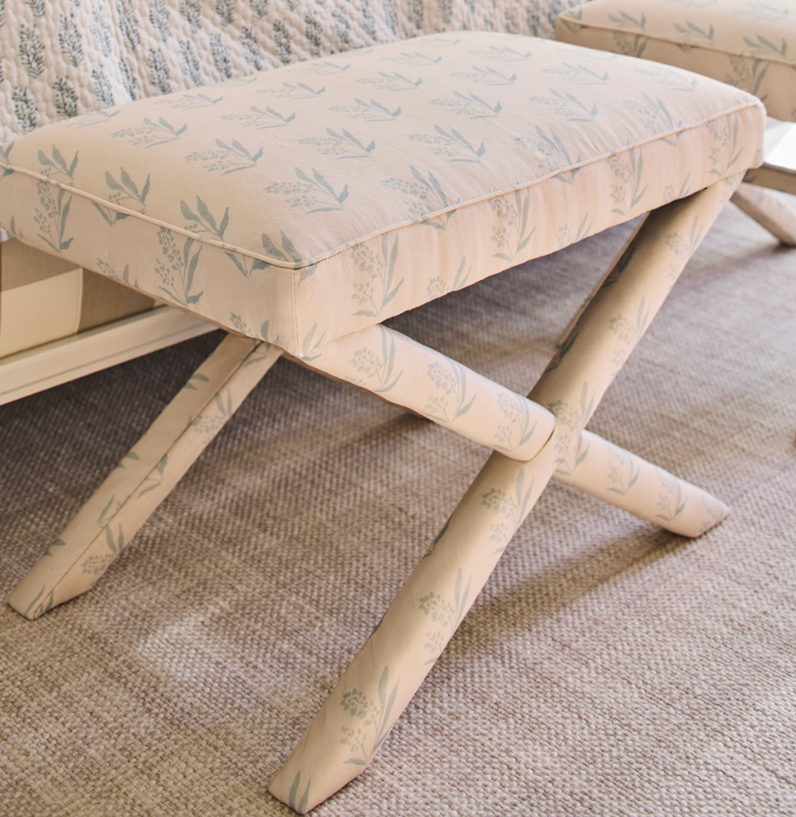 EH x Renee Bouchon Marbella Sea linen fabric on a light-colored X-bench with a botanical pattern.