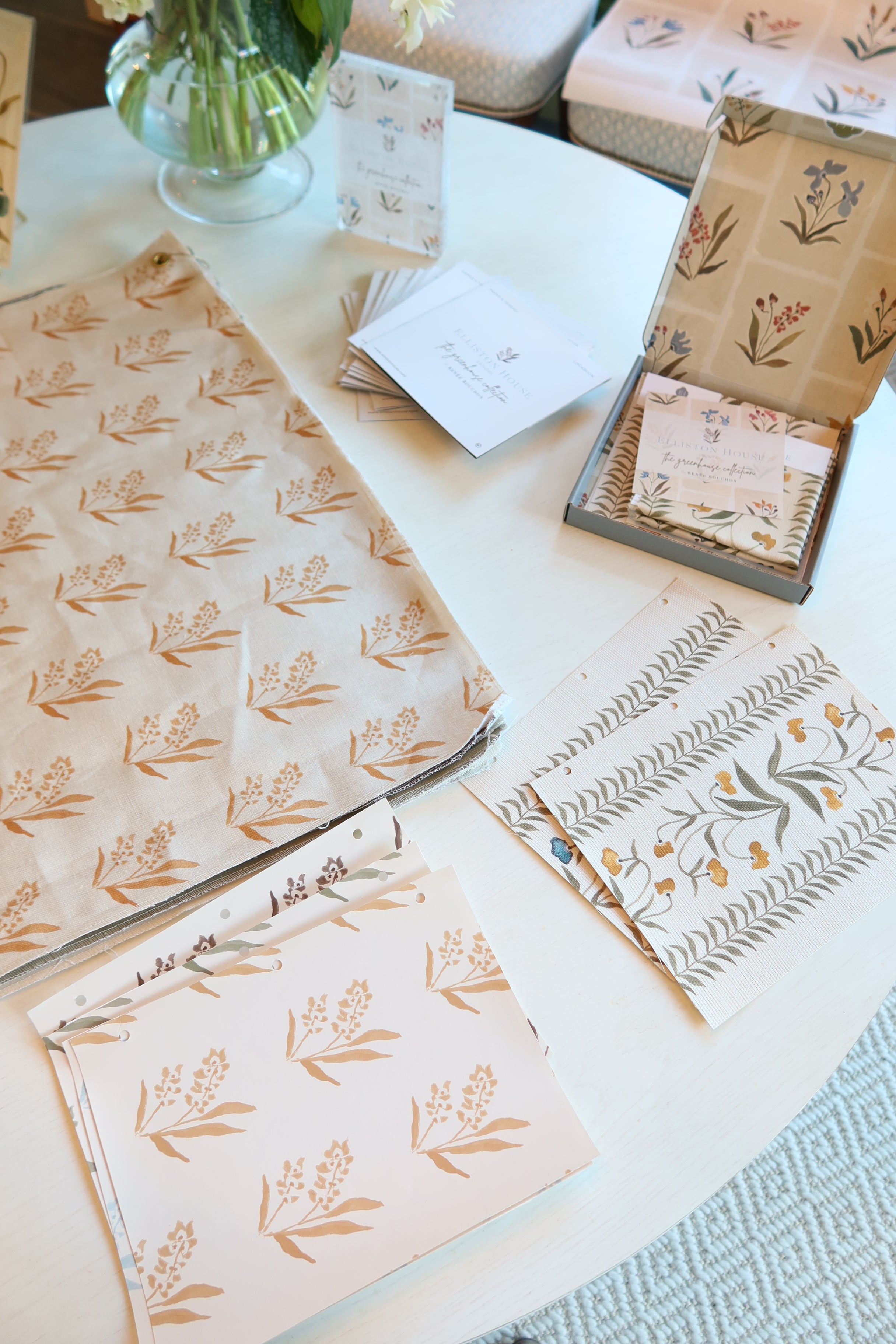 Marigold Marbella wallpaper yardage with a repeating floral pattern, alongside coordinating samples and stationery.