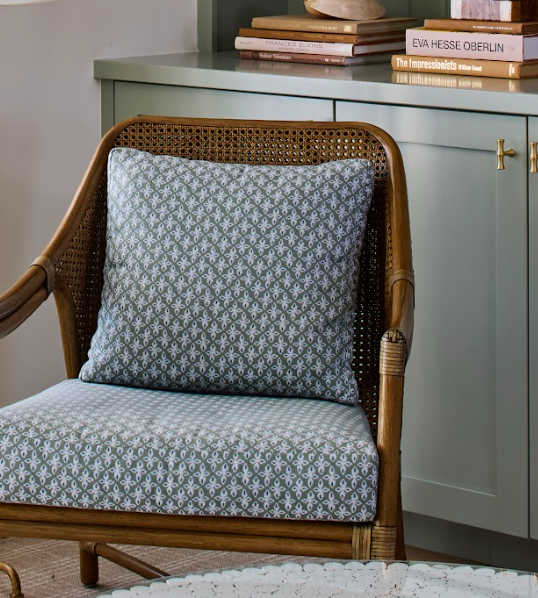 EH x Sunbrella Posey Fabric in Fern, a green and white patterned indoor-outdoor fabric on a rattan chair.