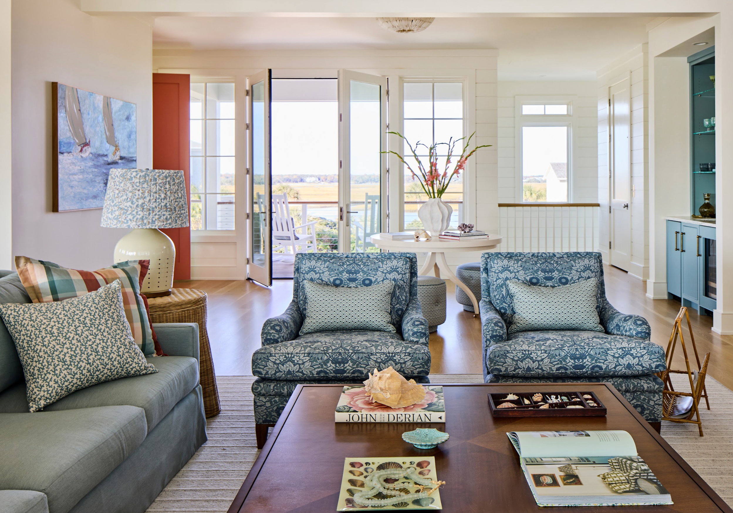 Coastal living room with blue floral upholstered chairs, light blue sofa, and a wooden coffee table.