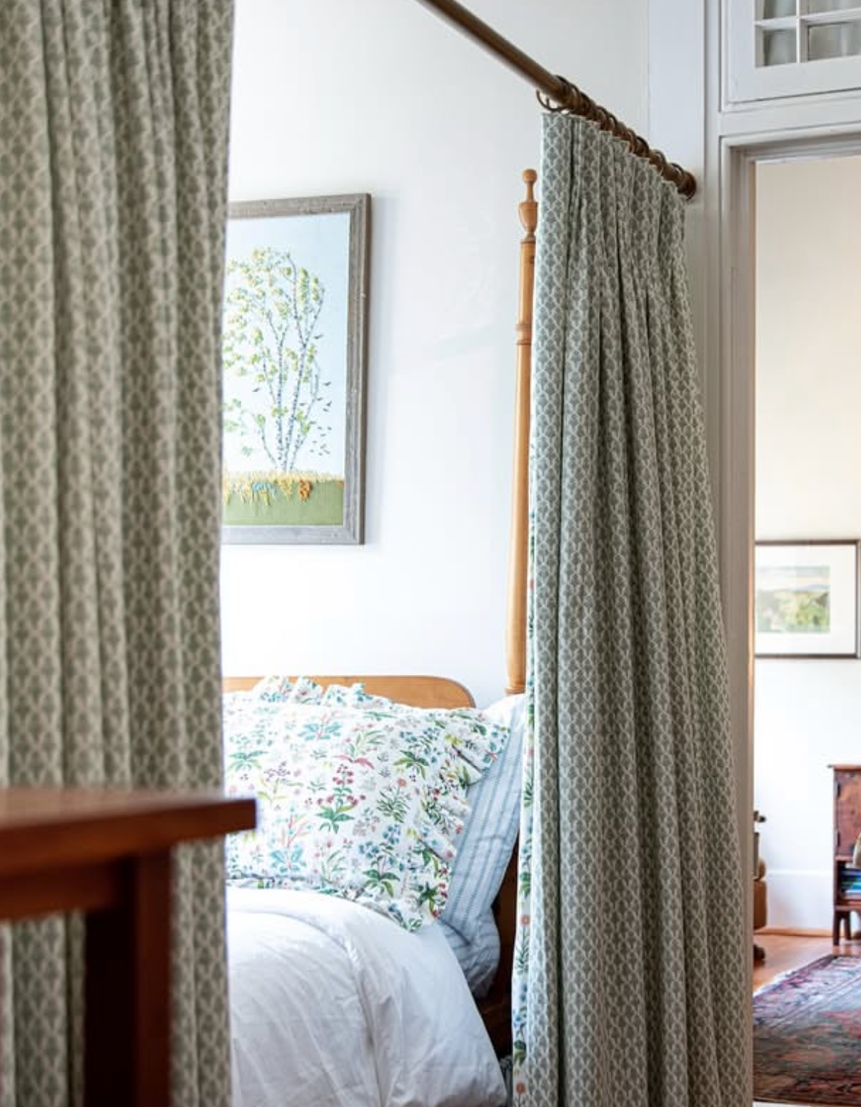 White Meadow Multi Fabric curtains with a subtle green geometric pattern, framing a wooden bed.