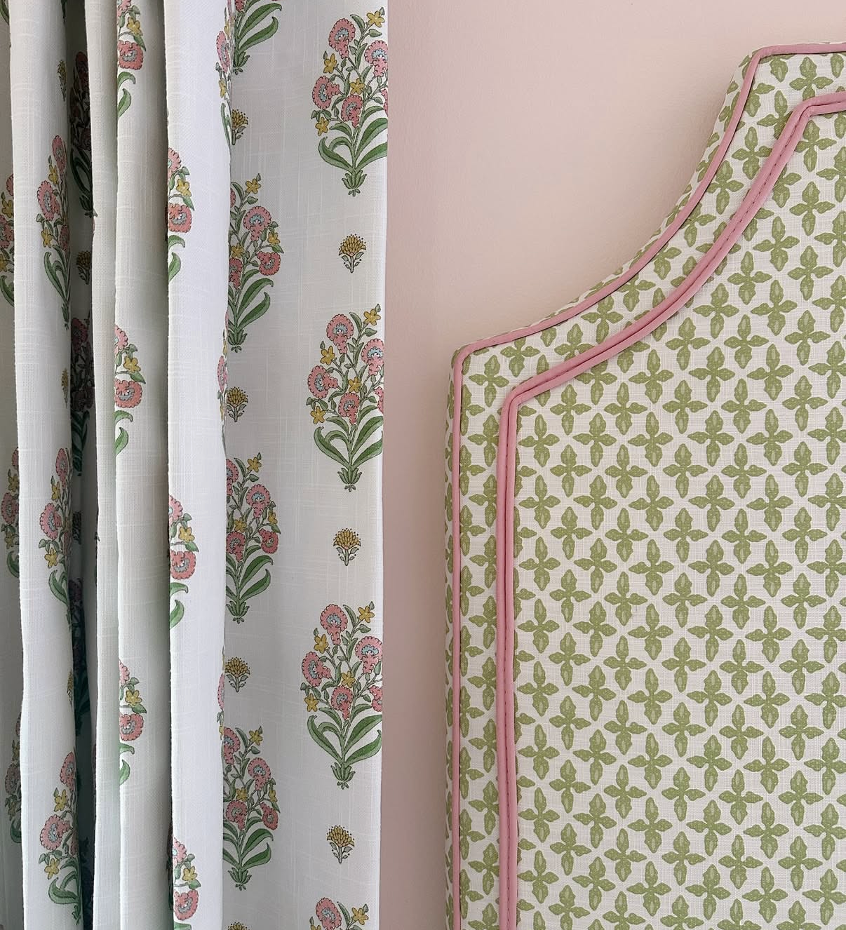 Posey Fabric "Apple" linen-cotton blend with pink floral pattern, next to a green patterned headboard with pink piping.