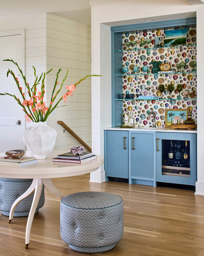 Marine Della Dot fabric on two round ottomans in a coastal-style room with a blue bar.