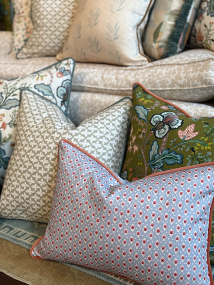 Della Dot Radish pillow, light blue with red dots, coral piping, among other patterned pillows on a sofa.