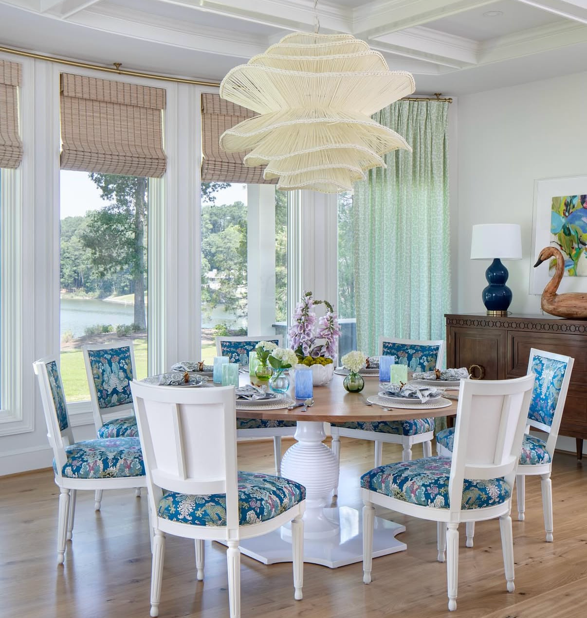 Dining room with white chairs upholstered in Dover Fabric - Apple, a blue and green floral linen-cotton blend.