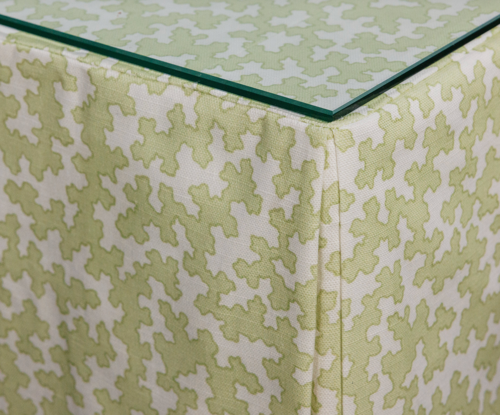 Dover Fabric in Apple, a linen-cotton blend with a light green geometric pattern, draped under glass.