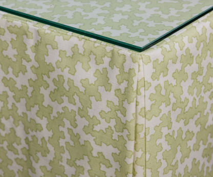 Dover Fabric in Apple, a linen-cotton blend with a light green geometric pattern, draped under glass.