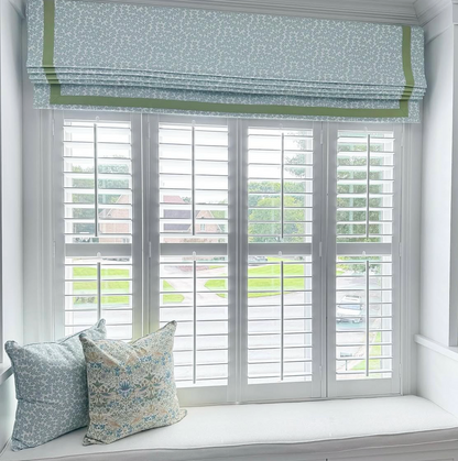 Dover Fabric - Pool linen-cotton blend Roman shade with green trim and two matching floral pillows.