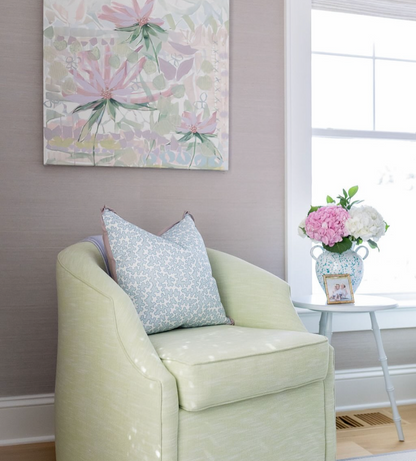 Dover Fabric - Pool: light green linen-cotton blend chair with a blue patterned pillow and floral artwork.