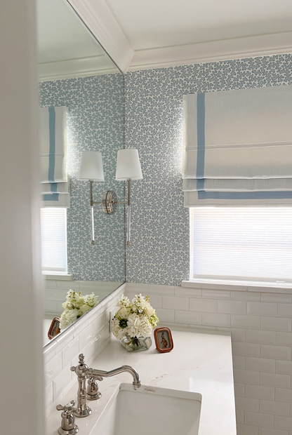 Dover Wallpaper in Pool, a light blue clay coated wallpaper with a subtle floral pattern, in a bathroom.