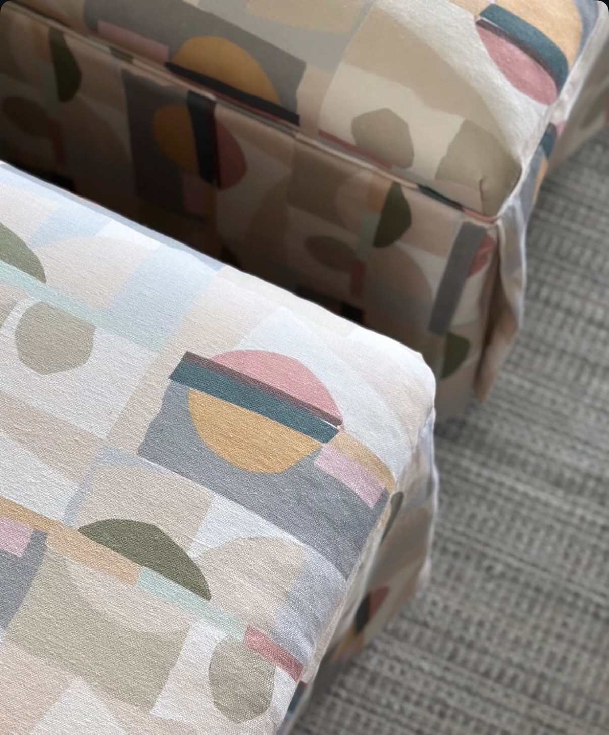 EH x Renee Bouchon Kipsy multi-color abstract linen fabric on two upholstered ottomans.