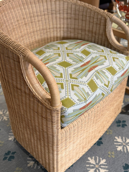 Woven wicker chair with a multi-colored EH x Sunbrella Arlo fabric cushion featuring a geometric pattern.