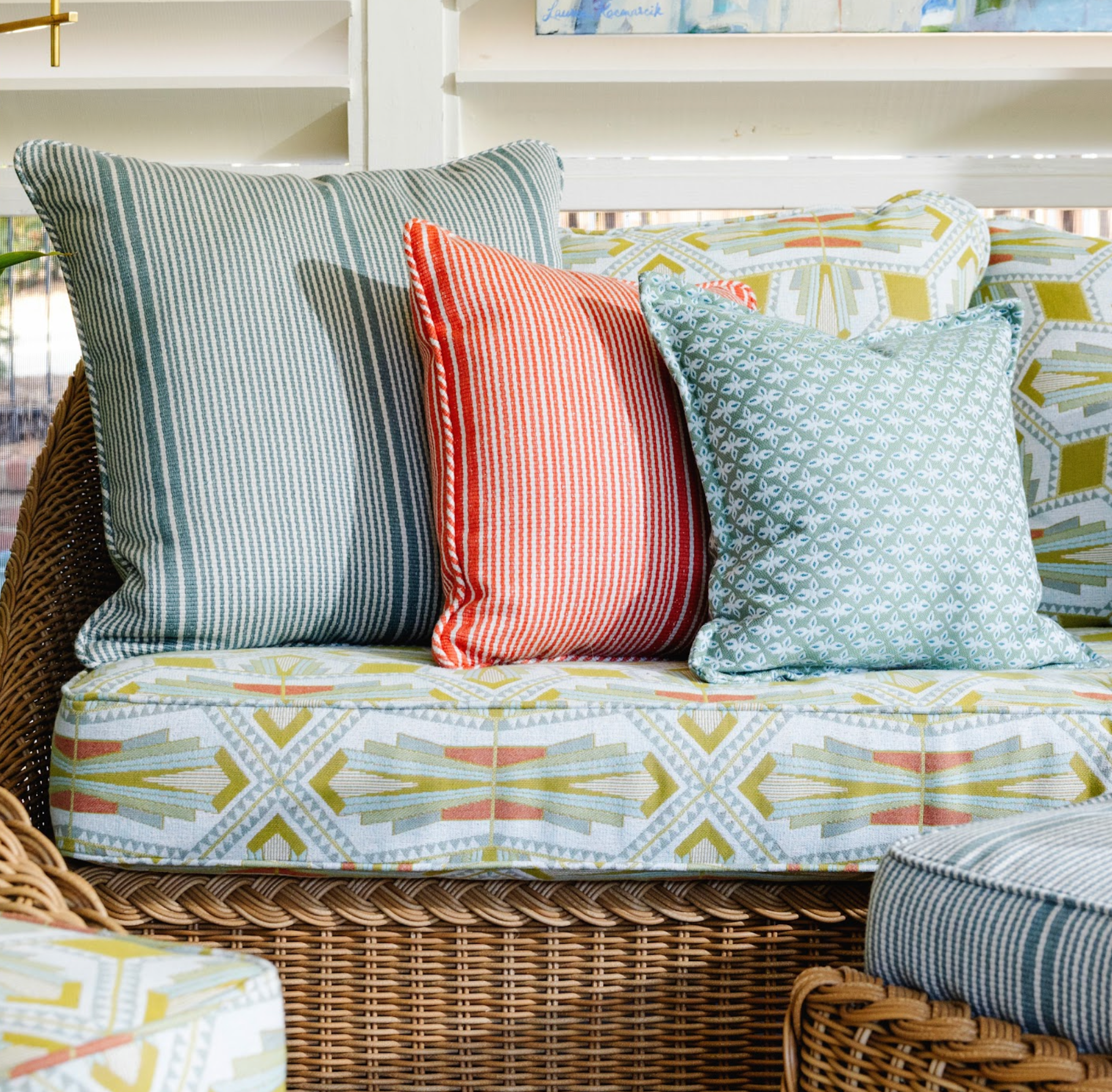 EH x Sunbrella Arlo Multi fabric on a wicker sofa with striped and patterned pillows.