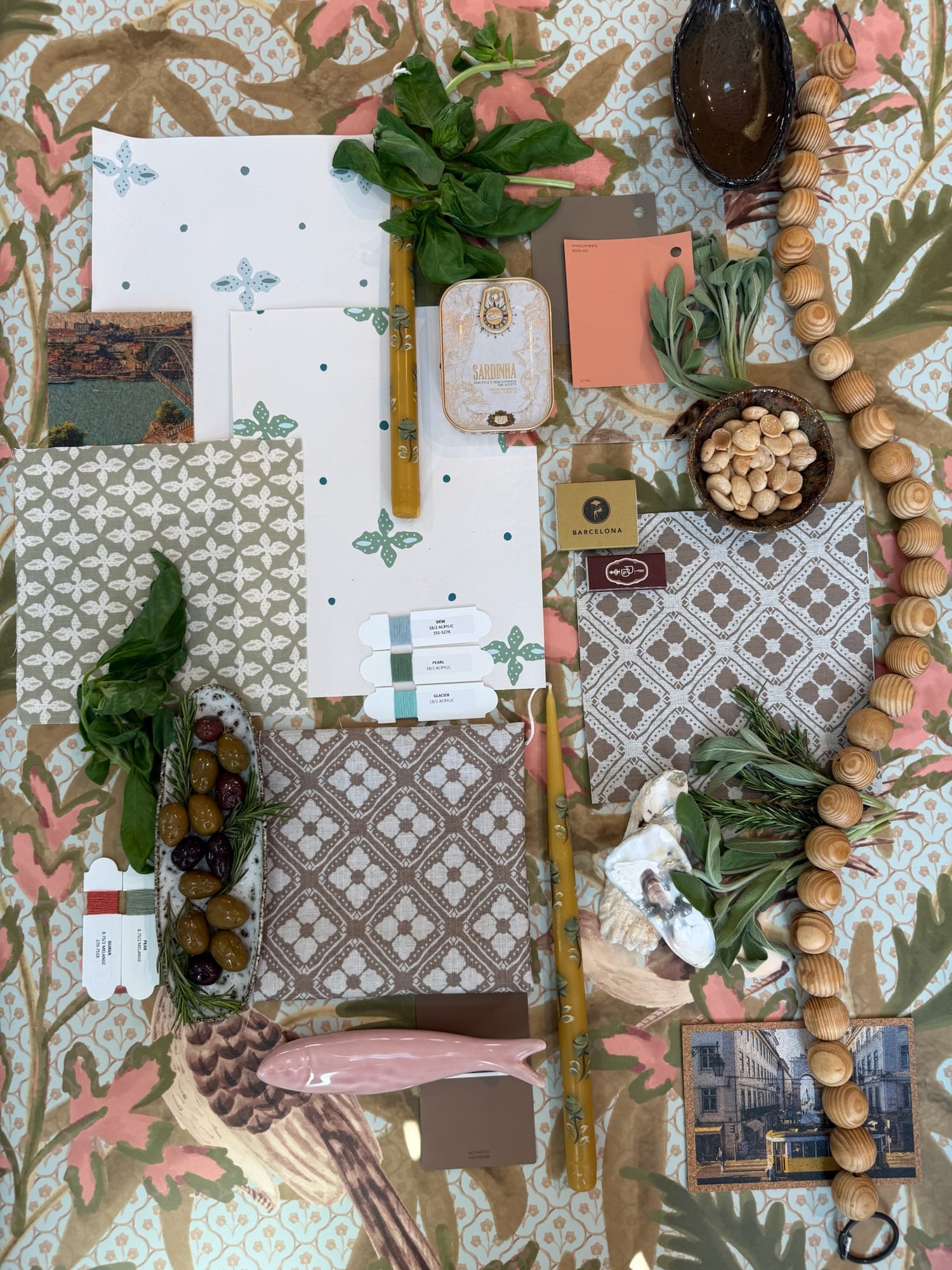Sparrow Fabric in Sea Salt linen, a flat lay with design swatches, olives, herbs, and wooden beads.