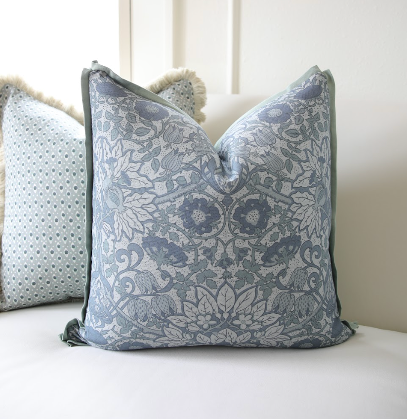 Cobalt Flora Fabric pillow with intricate blue floral and leaf pattern, light green piping, on a white sofa.
