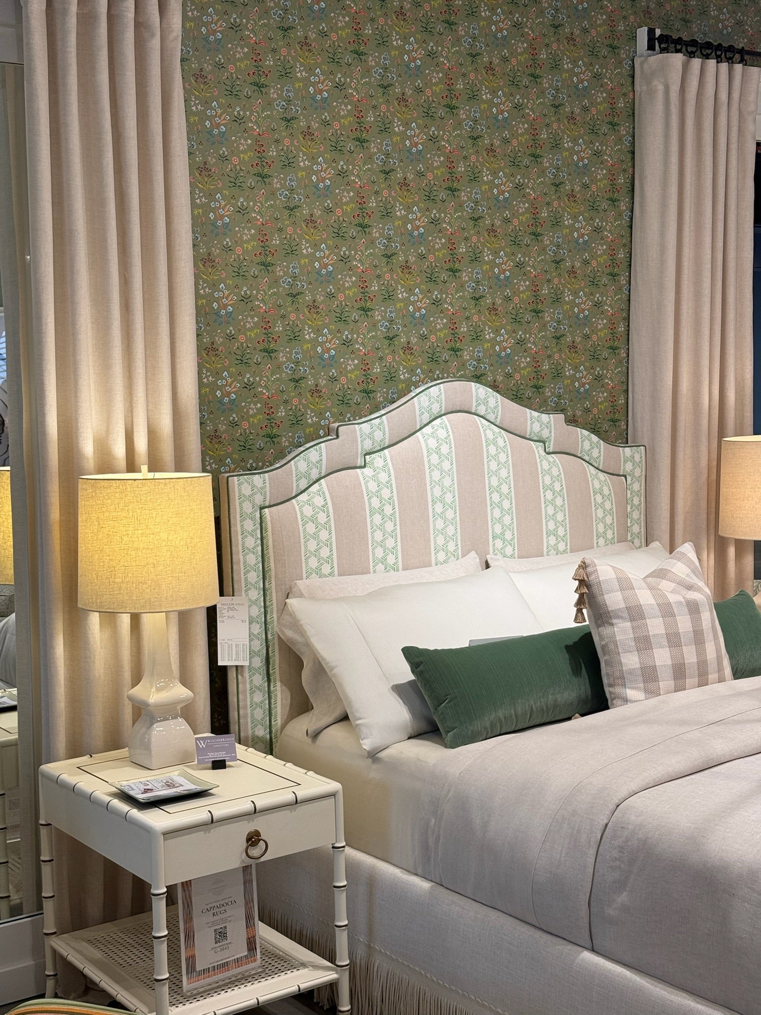 Meadow Multi Wallpaper in House Green with a striped upholstered headboard, neutral bedding, and a white nightstand.