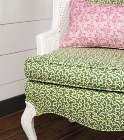 Laurel Fabric - Poppy, a green linen-cotton blend with a subtle floral pattern, upholstering a white chair.
