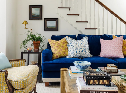 Laurel Fabric - Poppy on a blue velvet sofa with yellow, blue, and pink floral pillows.