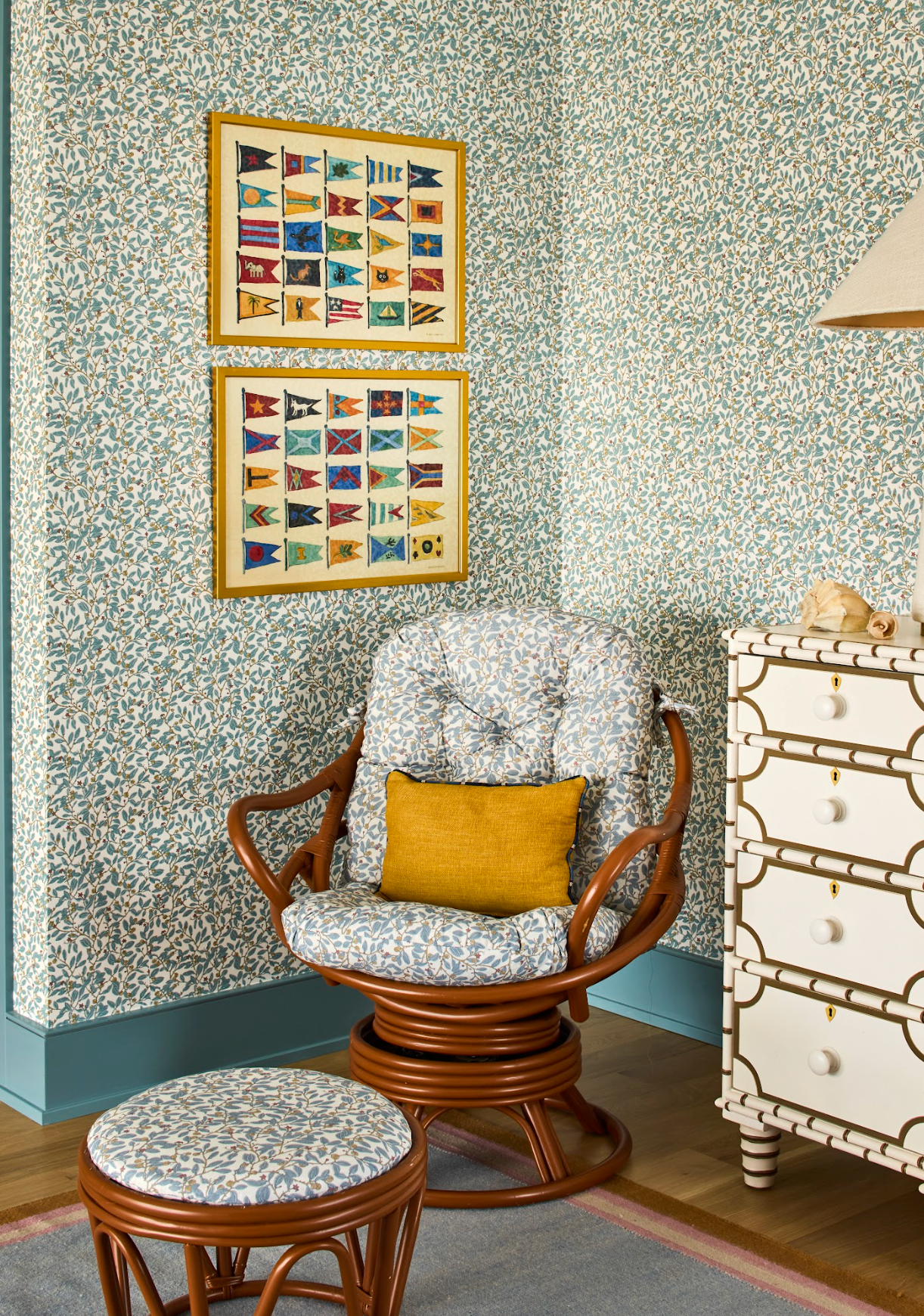 Blue Limes Wallpaper with a subtle leaf pattern, adorning a room with a rattan chair and nautical flag art.