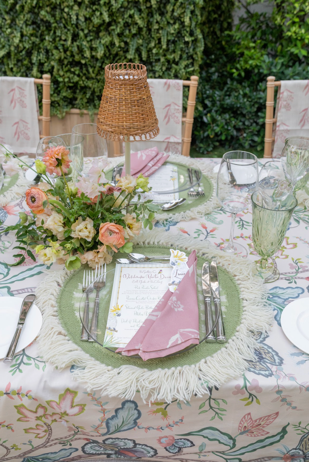 Marbella Pink RB x EH cotton napkins, folded on a set table with floral tablecloth and green fringed placemats.