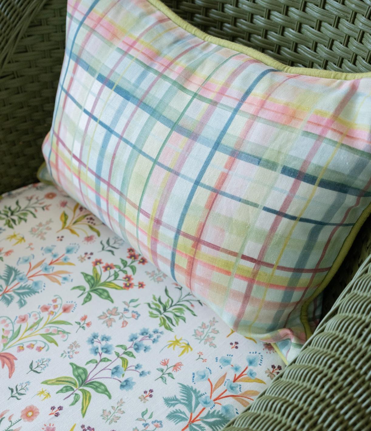 Meadow Multi Fabric in White, a colorful plaid linen pillow on a floral upholstered chair.