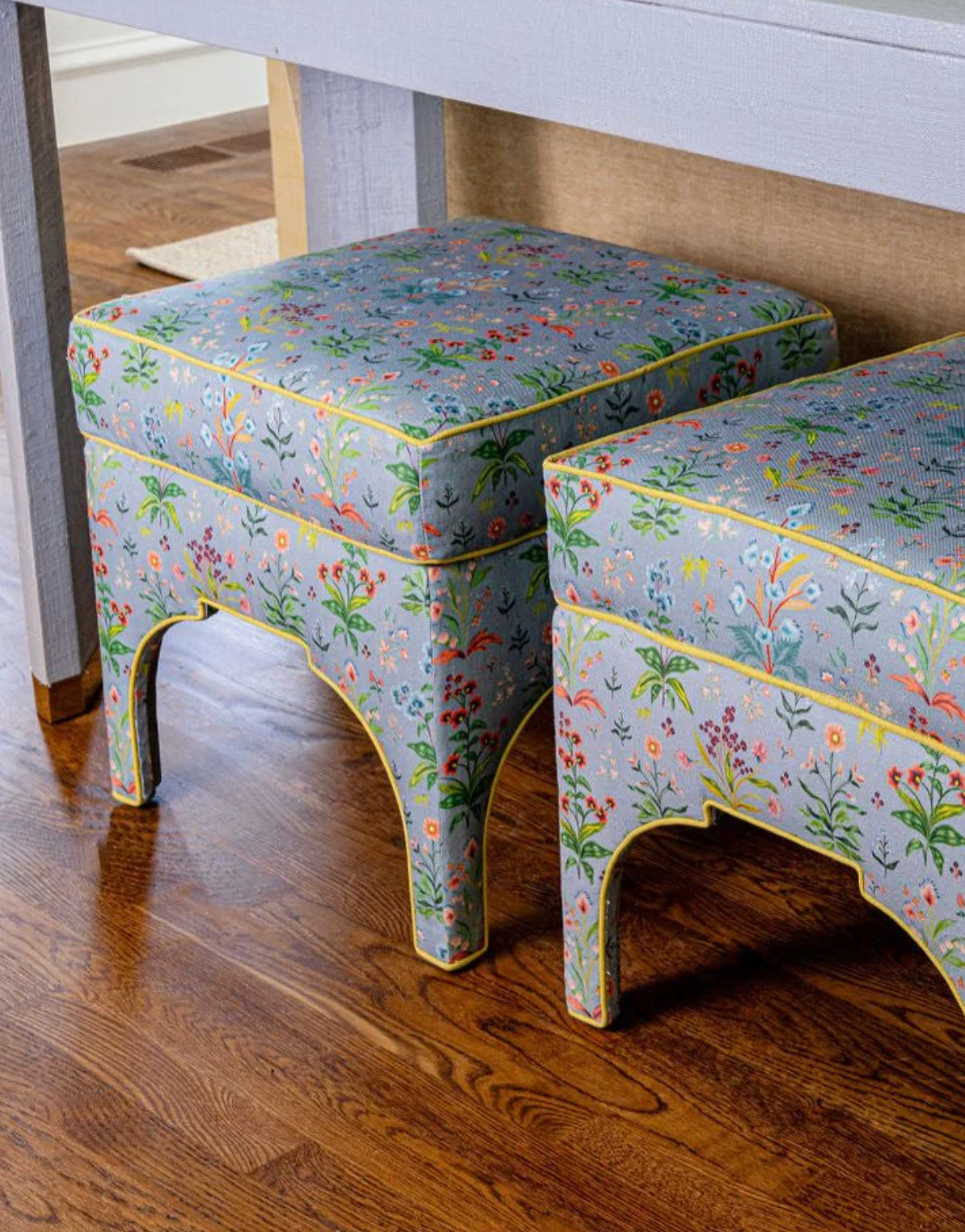 Two Meadow Multi Fabric ottomans in House Blue 100% Belgian Linen with colorful floral print and yellow piping.