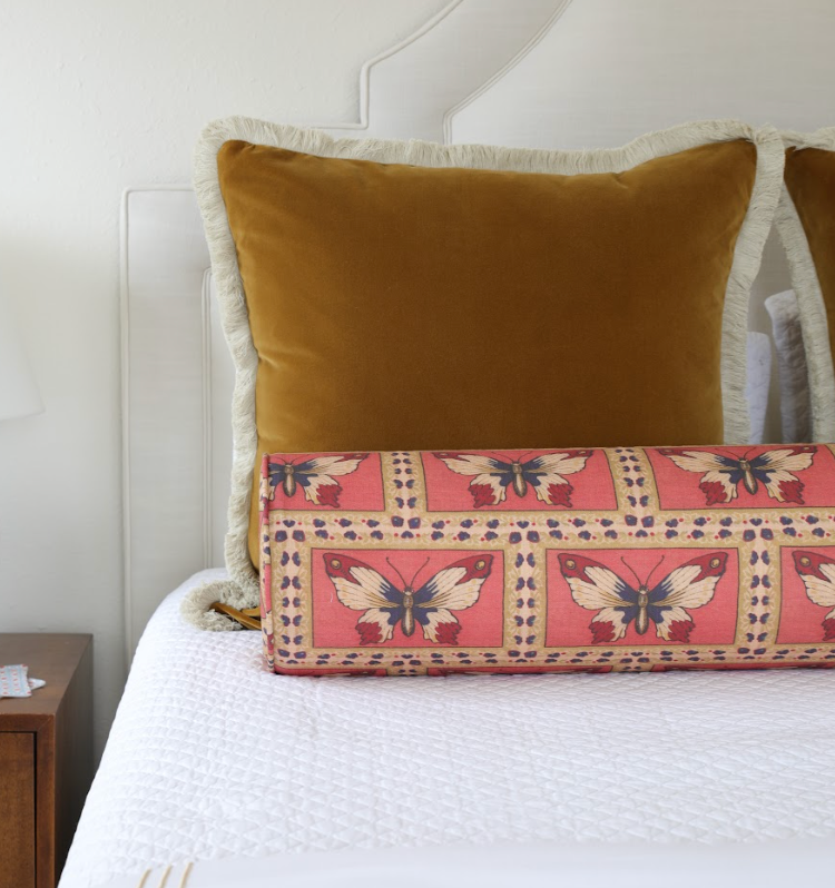 Monarch Fabric - Rouge, linen-cotton blend, with butterfly pattern on a bolster pillow.