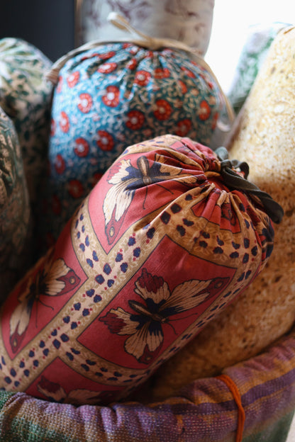 Monarch Fabric - Rouge, a linen-cotton blend with a butterfly pattern, rolled and tied.