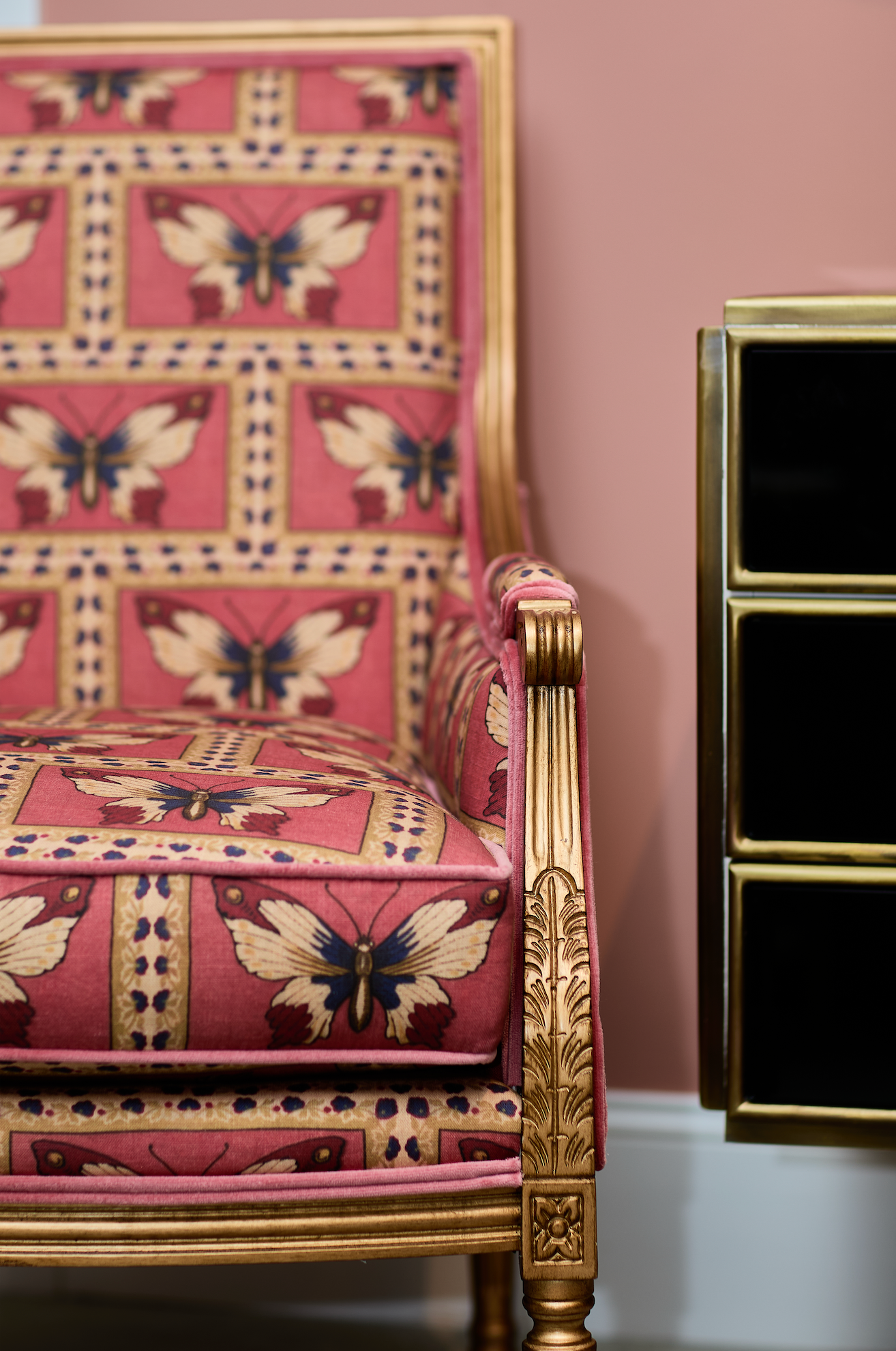 Monarch Fabric - Rouge on a chair, featuring a linen-cotton blend with butterfly patterns and gold trim.