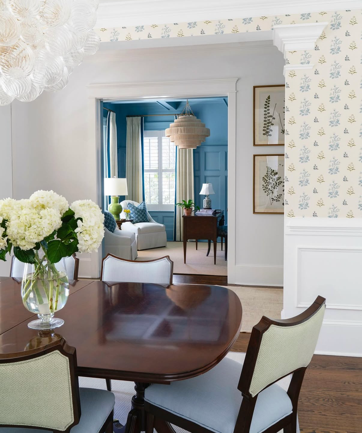 Perennial Grasscloth in Sprout, a cream wallcovering with delicate blue and green floral sprigs, in a dining room.