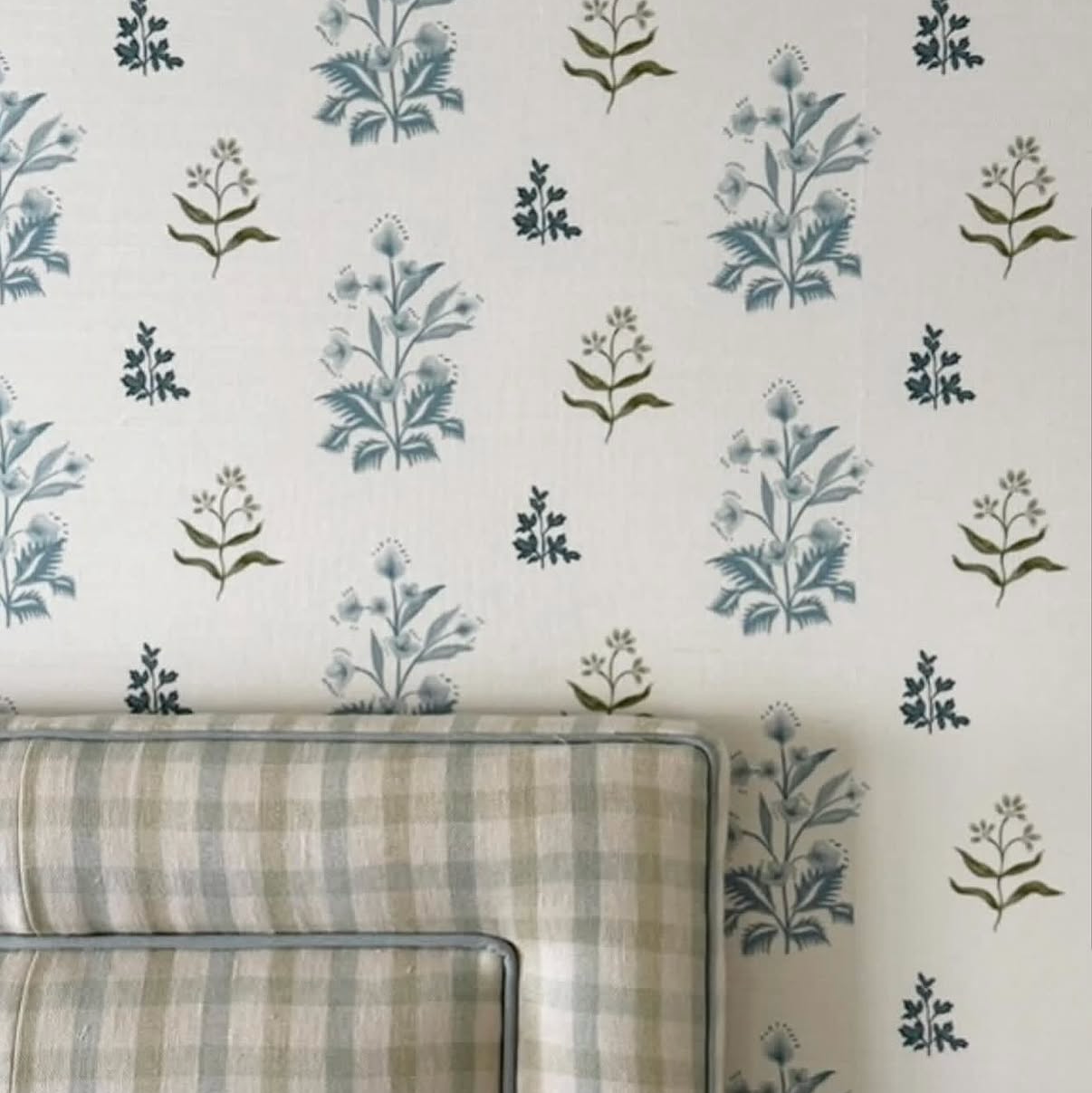 Perennial Grasscloth - Sprout wallpaper with blue floral sprigs on a white background, above a plaid headboard.