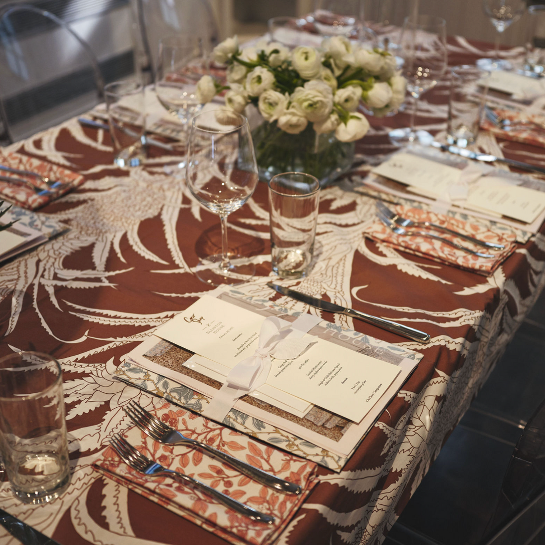 Pink Limes cotton dinner napkins with a floral pattern, set on a patterned tablecloth with place settings.