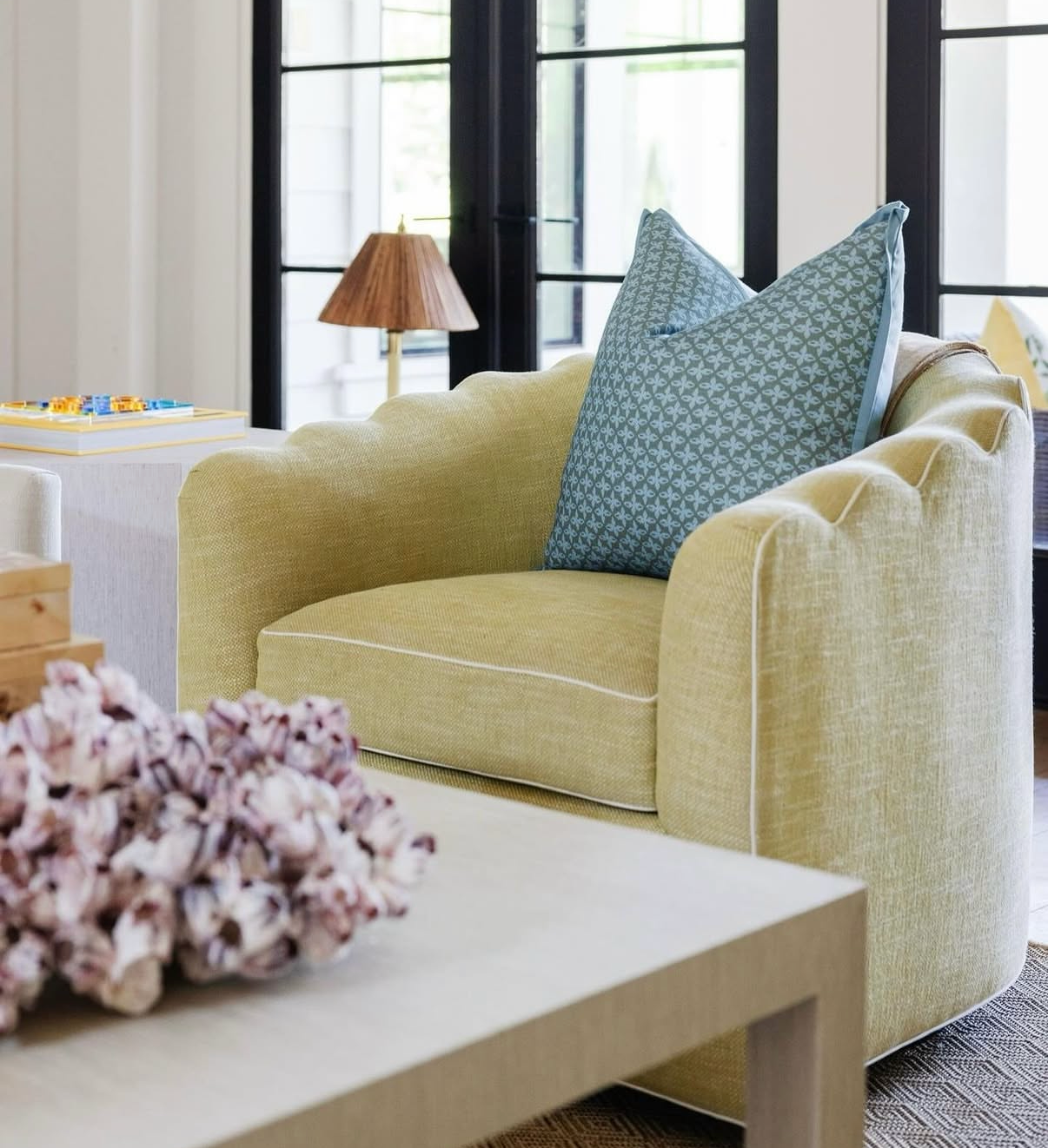 Posey Fabric in Moss, a linen-cotton blend, on a scalloped armchair with blue patterned pillow.