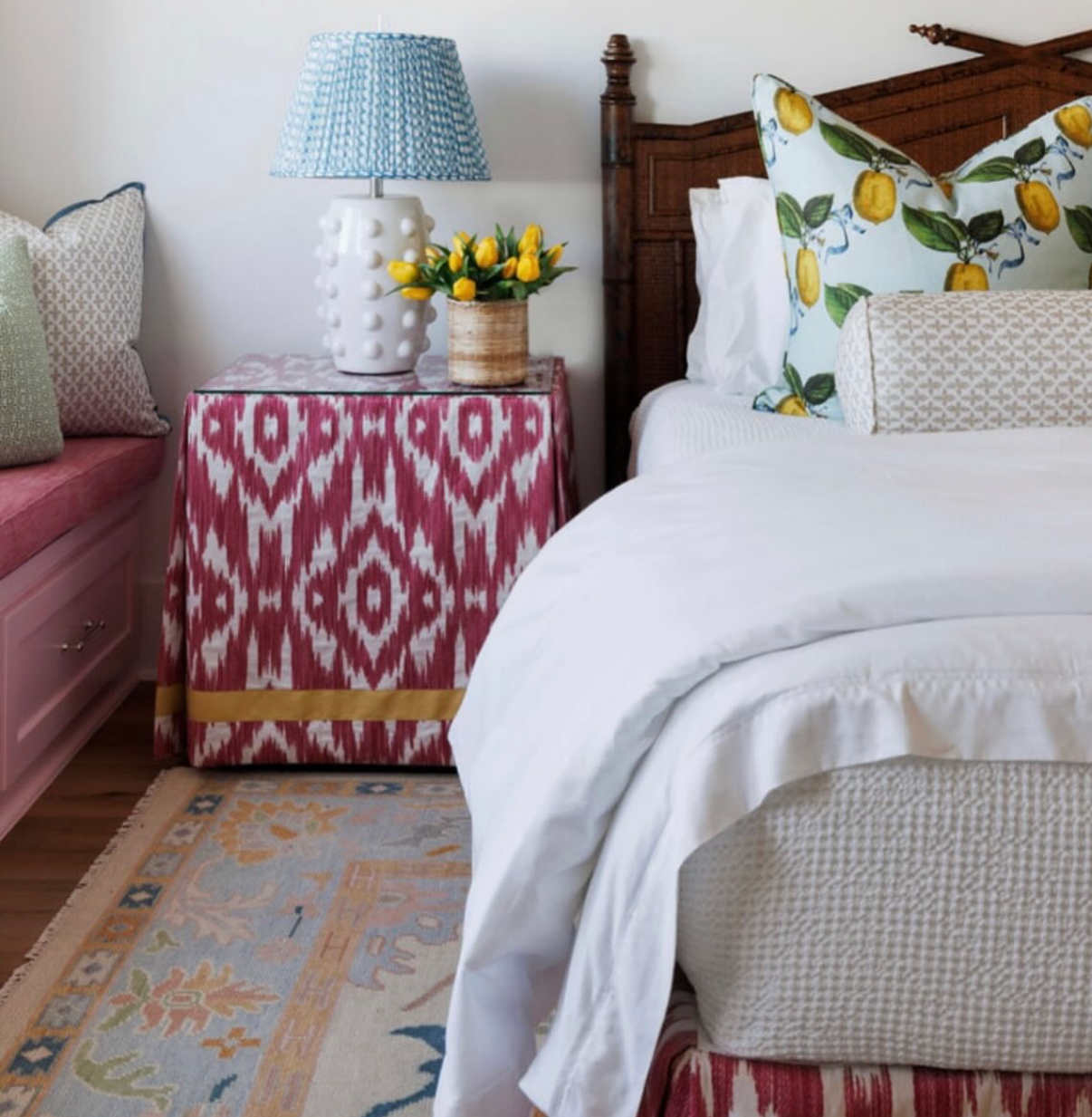 Posey Fabric - Sand, a linen-cotton blend, covers a nightstand in a bedroom with a blue lamp and lemon pillows.