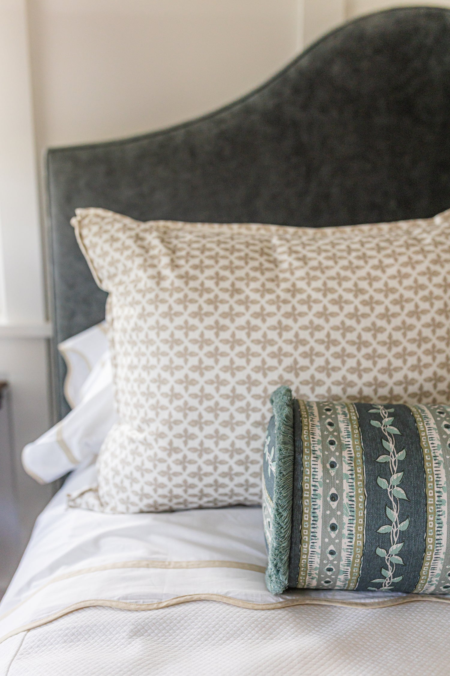 Posey Fabric in Sand, a linen-cotton blend with a subtle geometric pattern, on a bed.