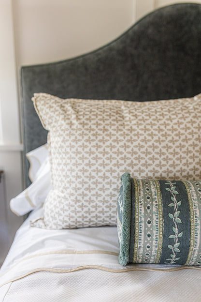 Posey Fabric in Sand, a linen-cotton blend with a subtle geometric pattern, on a bed.