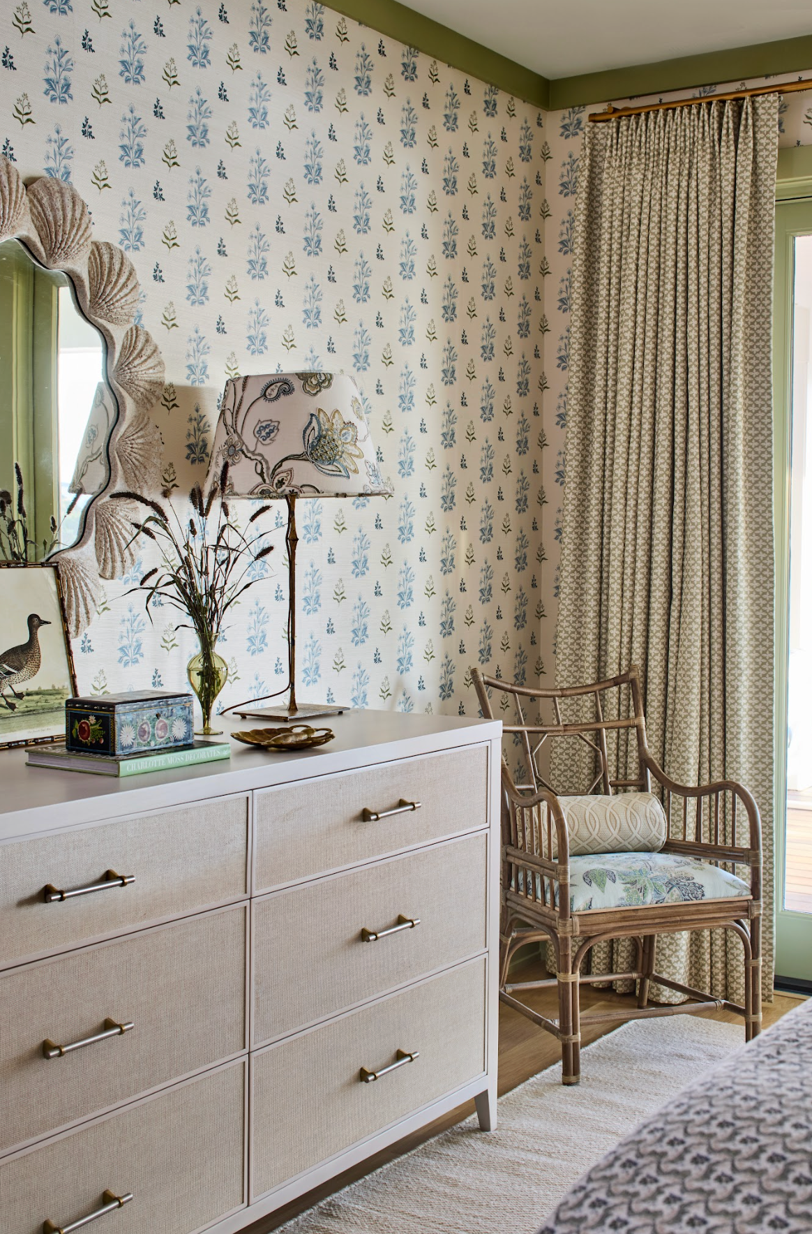 Perennial Grasscloth - Sprout wallpaper with blue floral pattern, a beige dresser, and a rattan chair.