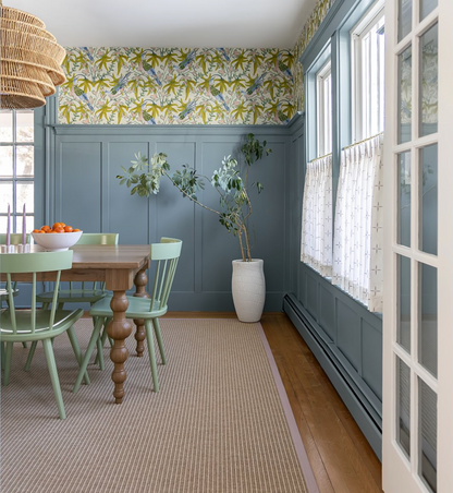 Sparrow Wallpaper - Citrus, a wide-width recycled content wallpaper, with a green and yellow botanical pattern above blue wainscoting.
