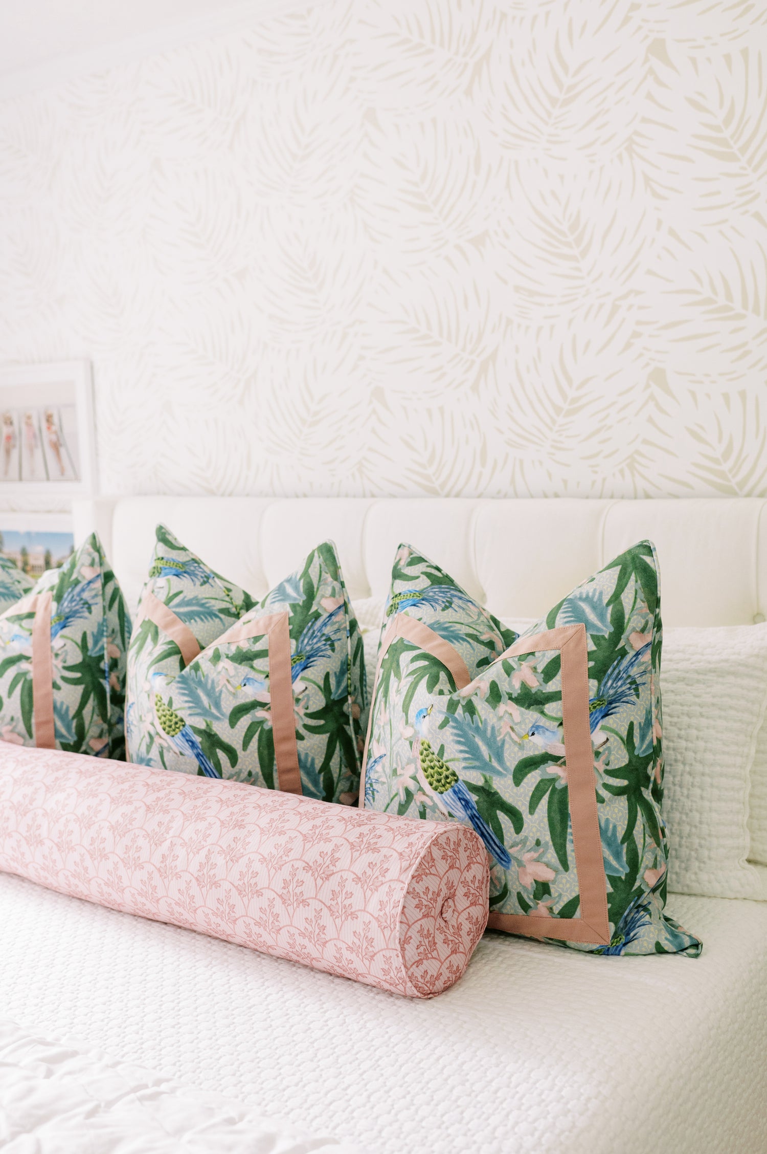 Laurel Fabric - Poppy: linen-cotton blend pillows with tropical birds and foliage, plus a pink patterned bolster.