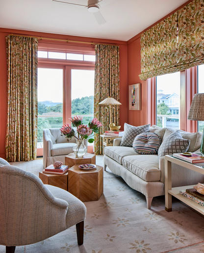 Living room with coral walls, linen Sparrow Fabric curtains, and a beige sofa.