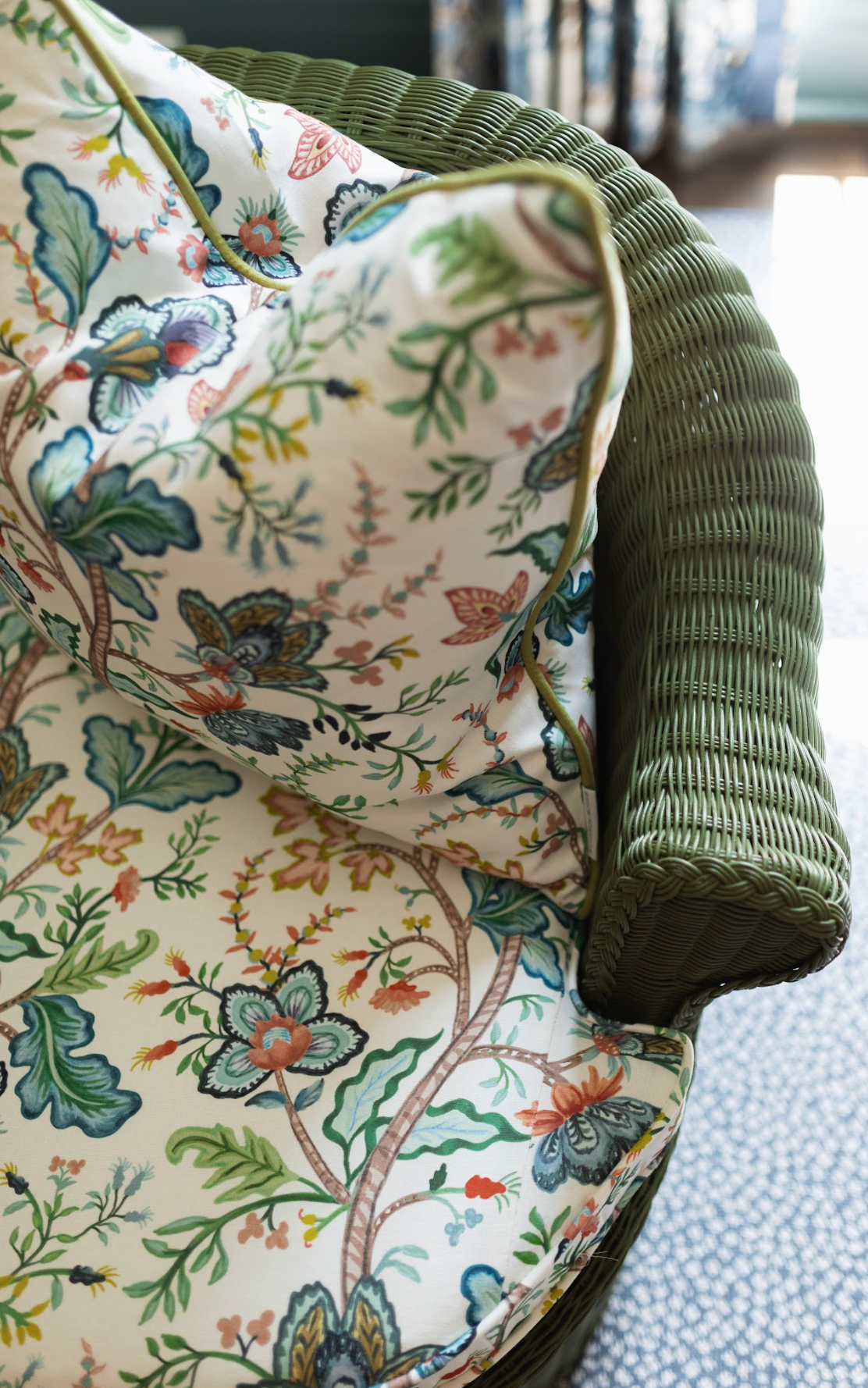 White Vera Vine 100% Belgian Linen fabric with colorful floral and vine pattern on a green wicker chair.